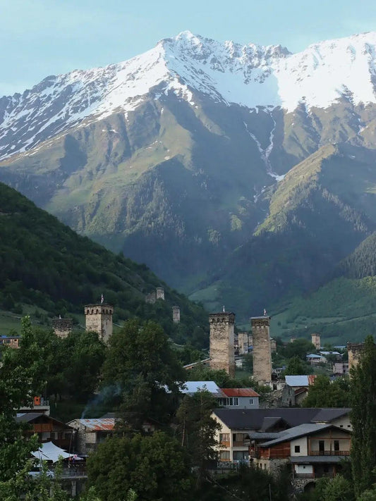 Medieval stone towers near snow-capped mountains in Wushu’s hometown, ideal for outdoor hiking.