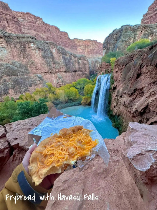 Frybread with cheese on a plate in front of Havasu Falls in the Grand Canyon.